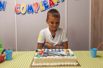 little boy with candles on cake waiting for gifts at birthday party