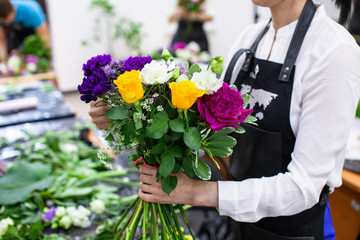 Female florist create a bouquet at workplace. Floristics workshop. Making beautiful flower bouquets...