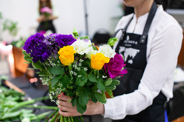 Female florist create a bouquet at workplace. Floristics workshop. Making beautiful flower bouquets...