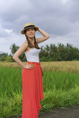 Beautiful young woman in red long maxi skirt with  straw hat and bag. Girl travel in Ubud, Bali, Indonesia