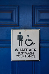 Sign on a blue restroom door says "Whatever Just Wash Your Hands" and includes male, female, and handicapped symbols