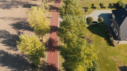 Aerial view of a bicycle highway in The Netherlands in a suburban environment with tall autumn trees along the side