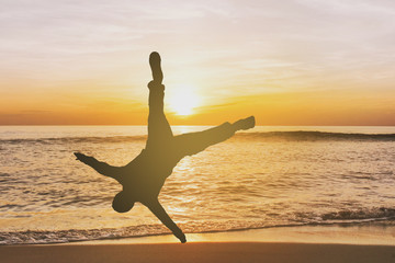 A Silhouette man jumping for joy on sunset beach