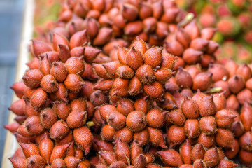 Fototapeta premium The background of the close-up fruit that is sold on the wooden table(rambutan,taking with a little thorn)is colorful,appetizing,sweet flavor,often cultivated according to the season, but the species