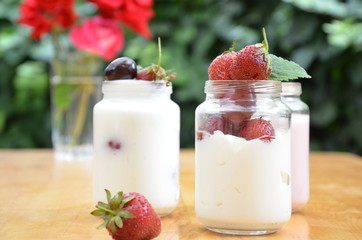 Healthy breakfast - granola, strawberries, cherry, honeysuckle berry, nuts and yogurt in a bowl. Vegetarian concept food. Top view. pudding or cocktail on the background of green foliage