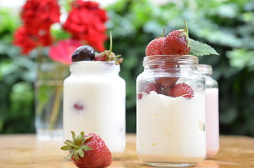 Healthy breakfast - granola, strawberries, cherry, honeysuckle berry, nuts and yogurt in a bowl. Vegetarian concept food. Top view. pudding or cocktail on the background of green foliage