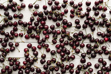 top view of fresh, sweet and ripe cherries covered with water drops on wooden background