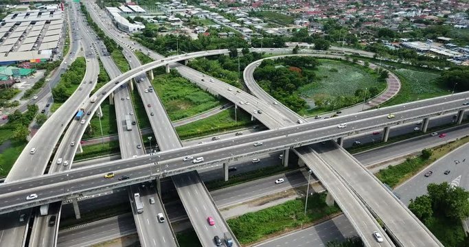 4K. Aerial view of road interchange of highway intersection with busy urban traffic speeding on the road. Junction network of transportation taken by drone.