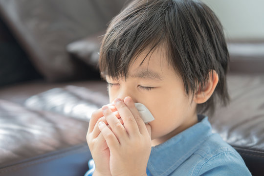asian little boy get cold and blow her nose, Sick child in room under blanket blowing his nose