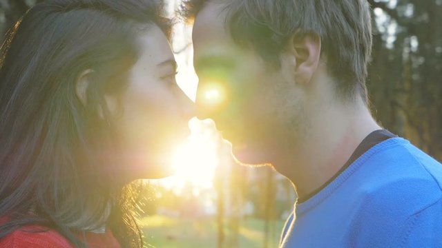 Love,Romance,Ttraction.Young couple kissing at sunset in the park