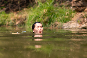 Asian woman swimming in river