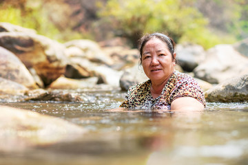 Asian woman in stream water for relaxing on vacation
