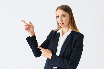 Beautiful young businesswoman pointing at something on white background