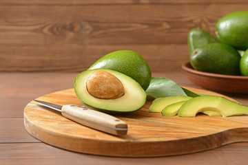 Fresh ripe avocados with knife on cutting board