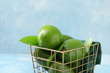 Basket with fresh ripe avocados on color background