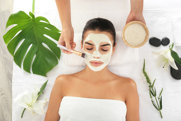 Cosmetologist applying mask on woman's face in spa salon
