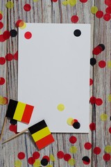 national day of Belgium , July 21. national Belgian festival. the concept of celebration, fun, patriotism and freedom. mini flags and confetti with sheets of white paper on white wooden 