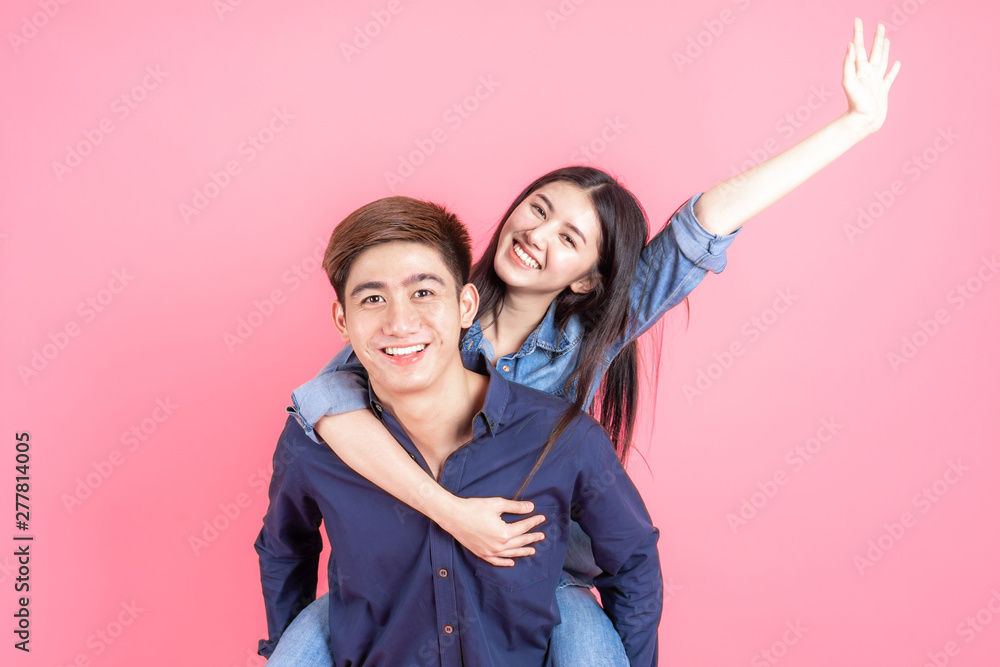 Wall mural portrait cheerful young couple on pink background