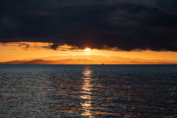 close up big Sun set, Sunrise with the cloud and mountain layer at the sea., Thailand.