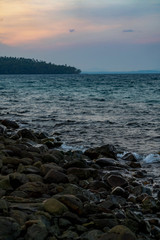 Black dark stone on the beach in the sea with a little snails all that area. It's twiligt time in Asian, Thailand.