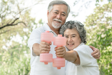 Cheerful elderly Asian man and senior Asian woman with dumbbell for workout in park, They smiling with good healthy together