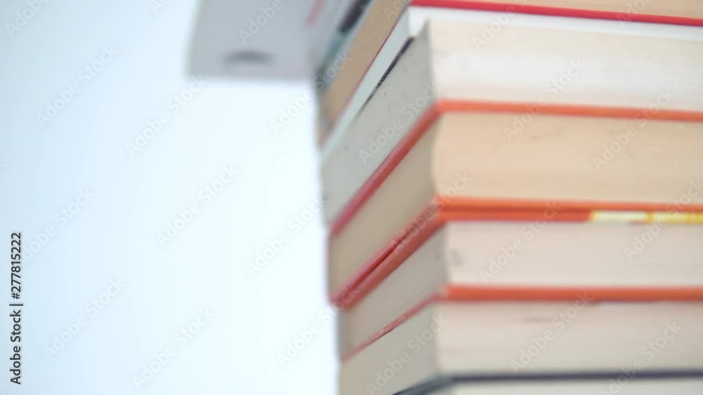 Poster a stack of books with colourful covers is on the table. slow movement from top to bottom. the books 
