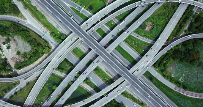 4K. Aerial view of road interchange of highway intersection with busy urban traffic speeding on the road. Junction network of transportation taken by drone.