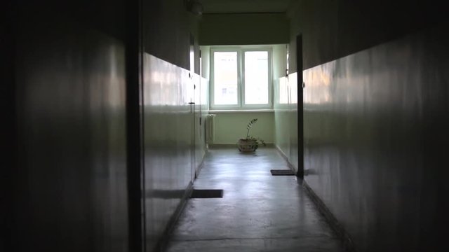 Slow motion in an old dark empty corridor in a block of flats, a stylized place with a window at the end of the corridor, camera movement from floor to ceiling