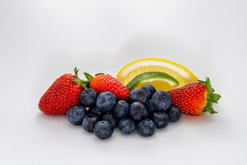 An arrangement of fresh blueberries, strawberries, lemon and lime isolated on white.