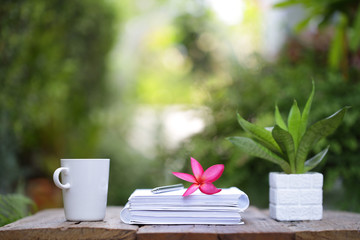 White coffee cup and notebooks on wooden table at outdoor