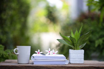 White coffee cup and notebooks on wooden table at outdoor