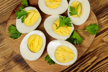 Boiled eggs with parsley on cutting board on a wooden table. Top view