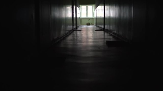 A static shot in an old dark empty corridor in a block of flats, a stylized place with a window at the end of the corridor, a view of the floor