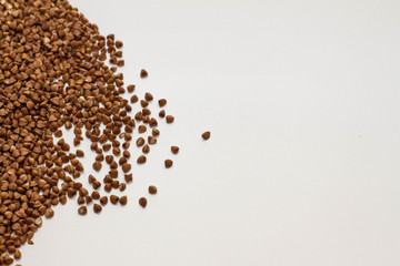 natural buckwheat scattered on a white background. Buckwheat grains on a white table. Brown buckwheat for proper nutrition