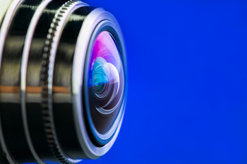 Camera lens with blue backlight. Side view of the lens of camera on blue background. Blue camera Lens close Up.