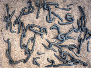 Metal chains - abstract  background. Ships anchor chain lying on the beach sand. Pattern of old ship anchor chain links close-up. Grunge Vintage Style Background.