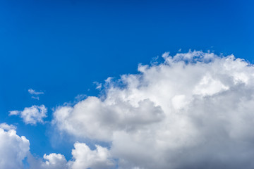 Fluffy white clouds against a bright, colorful blue sky