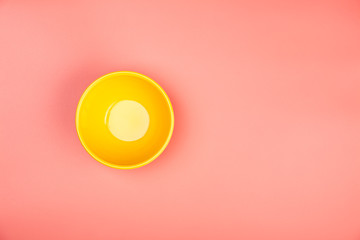 Yellow bowl on pastel pink background, flat lay
