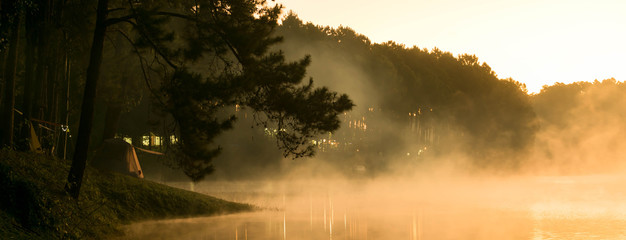 Camp site in national park in forest with lake in morning beautiful view of fog on surface water, dimension for banner