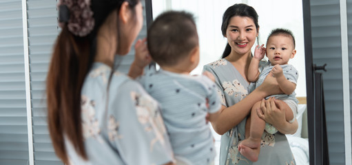 Mother play with 8 month old baby son face reflection in mirror