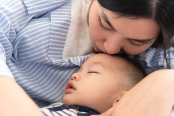 Mother kiss on her 8 months old baby fore head while sleeping