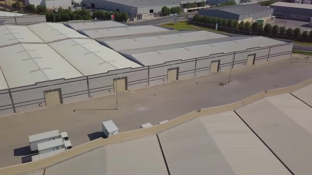 Storage facility warehouses side by side in the desert with some trees, grass, and garage door gates (4K)