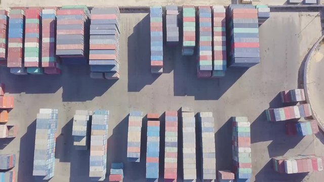 Birds eye view of a flyover a very large container yard with colorful containers, trucks, forklifts, and container loaders