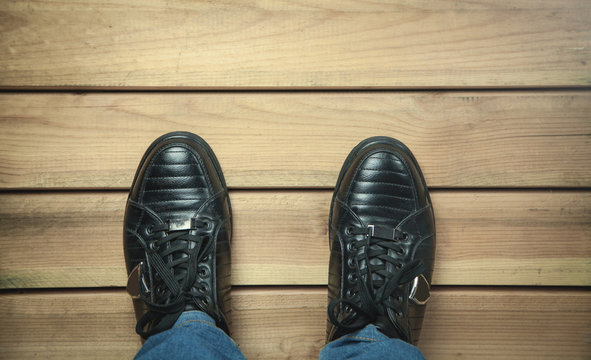 Black leather shoes on wooden floor.