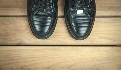 Black leather shoes on wooden floor.