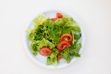 Spring salad with tomatoes on the white plate