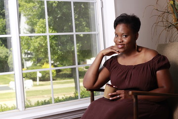 pretty black young woman smiling sitting in chair with coffee