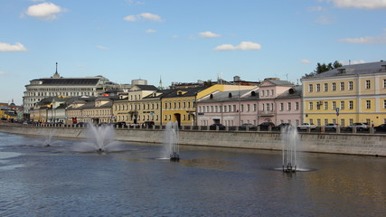 Fototapeta premium Russia, Beautiful colored old houses on Kadashevskaya embankment and water fountains on the Vodootvodny canal in Moscow on a Sunny summer day, panoramic cityscape