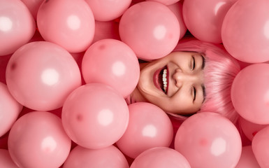Asian female laughing under pink balloons