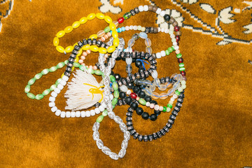 close up of multicolor muslim prayer beads on a prayer mate.